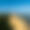 Las Landas: Vista aérea de la Duna de Pilat, una enorme duna de arena beige bordeada por un verde bosque de pinos a un lado y el océano azul claro al otro, bajo un cielo azul uniforme.