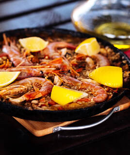 Une paella appétissante garnie de crevettes et de tranches de citron, présentée dans une poêle.