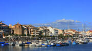 Panoramisch uitzicht op de haven van Cambrils in Spanje, met veel aangemeerde boten en kleurrijke gebouwen langs de kade onder een blauwe lucht.