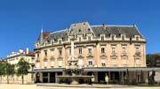 La Fontaine Monumentale de Valence avec un grand bâtiment de style Haussmannien en arrière-plan, sous un ciel bleu.