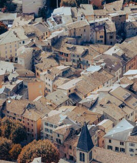 Vue panoramique du village de Castellane, niché au pied de son célèbre Roc, avec ses toits de tuiles rouges et son église, au cœur des Gorges du Verdon.