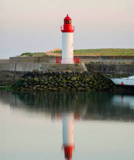 Phare blanc et rouge se reflétant dans l'eau calme, à Saint-Pierre-d'Oléron sur l'Île d'Oléron.