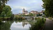 Vue panoramique sur la ville de Dole, avec la collégiale Notre-Dame reflétée dans la rivière.