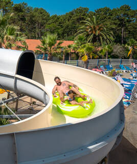 Père et enfant descendant un toboggan aquatique sur une bouée, à Atlantic Park, près de Mimizan.