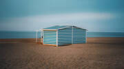 Cabine de plage à rayures bleues et blanches sur le sable, face à la mer, à Narbonne-Plage.