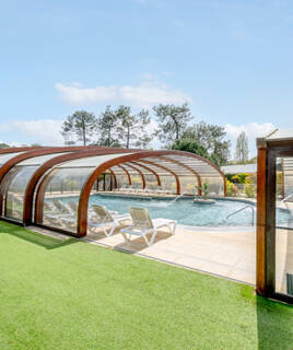 Piscine extérieure couverte avec transats et espace vert dans un camping.