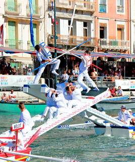 Joutes nautiques traditionnelles sur le Canal Royal de Sète, avec des jouteurs en plein affrontement sur leurs barques.