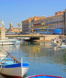 Canal à Sète avec des bateaux amarrés et des bâtiments colorés en arrière-plan, dans le quartier de la Pointe Courte.