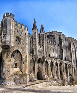 Le Palais des Papes à Avignon, une imposante structure médiévale avec ses tours et ses murs en pierre, situé près de Vallon-Pont-d'Arc.
