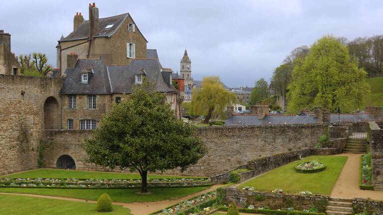 Tour et remparts médiévaux de la ville de Vannes, avec des fleurs colorées et un ciel bleu clair.