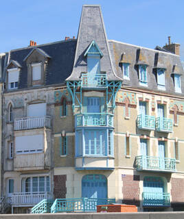 Une villa d'époque avec des balcons et une tour distinctive aux couleurs bleues et beiges, typique de l'architecture de la Baie de Somme, près du Touquet.