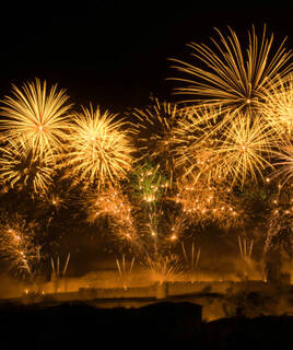 Un plat de cassoulet traditionnel de Carcassonne, servi dans une cocotte en fonte, contenant des haricots blancs, des saucisses, du confit de canard et de la poitrine fumée, posé sur une planche en bois rustique.