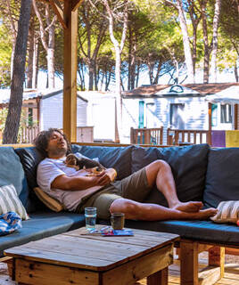 Homme faisant la sieste sur la terrasse de son mobil-home avec son chien