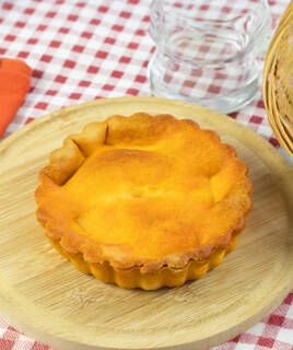 Une tielle de Sète, spécialité culinaire du littoral près de Frontignan, est présentée sur une planche en bois ronde, avec sa croûte dorée et son aspect savoureux, prête à être dégustée.