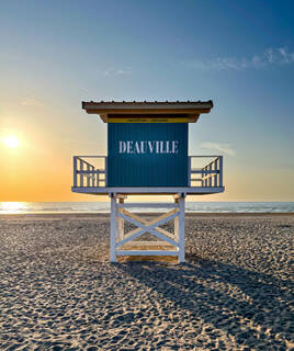 Cabine de sauveteur emblématique de Deauville, sur la plage de sable fin, au coucher du soleil.