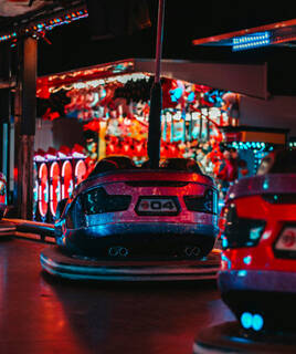 Des auto-tamponneuses lumineuses et colorées dans le Parc Bagatelle à Merlimont, avec des lumières néon rouges et bleues créant une ambiance festive de nuit.
