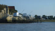 Plusieurs carrelets, ces cabanes de pêche sur pilotis avec leurs grands filets carrés, le long des rives de l'Estuaire de la Gironde près de Montalivet, sous un ciel bleu.
