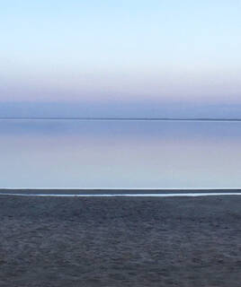 Les eaux calmes du Lac de Maubuisson, près de Montalivet, se fondant dans un ciel aux teintes pastel du crépuscule, vues depuis le rivage.