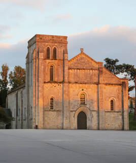 La basilique Notre-Dame-de-la-Fin-des-Terres à Soulac-sur-Mer, près de Montalivet, illuminée par la lumière du coucher du soleil, avec son architecture romane imposante.