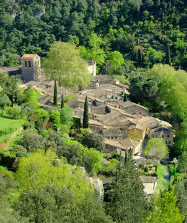 Vue aérienne du village de Saint-Guilhem-le-Désert, près de Montpellier, niché dans une vallée verdoyante avec ses maisons aux toits de tuiles et son abbaye romane.
