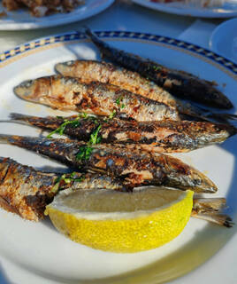 Des sardines grillées servies sur une assiette blanche avec un quartier de citron, une spécialité culinaire locale de Saint-Gilles-Croix-de-Vie.