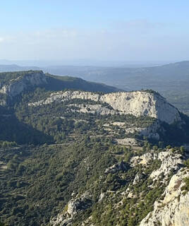 Vue aérienne des falaises calcaires du Mont Gros Cerveau, près de Sanary-sur-Mer, s'élevant au-dessus d'une forêt méditerranéenne luxuriante sous un ciel clair, offrant un panorama sur le paysage varois.