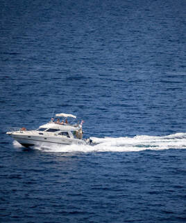 Une vedette blanche filant sur l'eau bleue, laissant un sillage mousseux, probablement en Méditerranée près d'Aix-en-Provence.