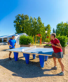 Un père et son fils faisant un tournois de ping-pong au camping