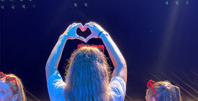 Animateur sur la scène qui fais un coeur au publque avec ses mains